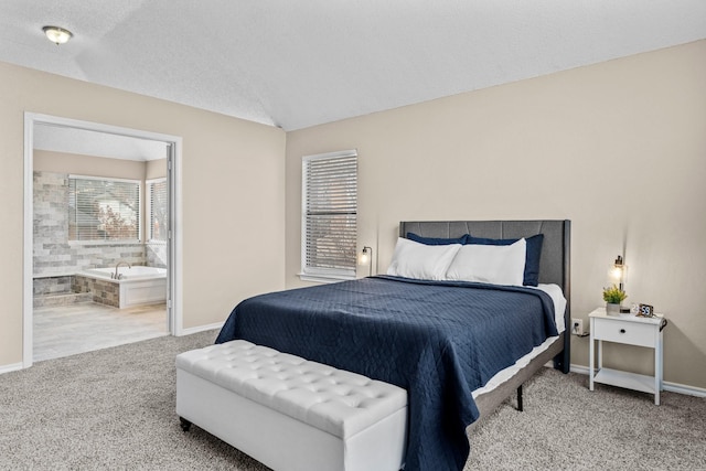 bedroom with a textured ceiling, carpet floors, ensuite bath, and lofted ceiling