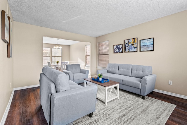 living room featuring a notable chandelier, wood-type flooring, and a textured ceiling