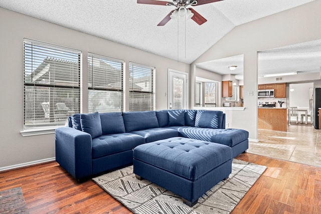 living room featuring a textured ceiling, light hardwood / wood-style flooring, ceiling fan, and lofted ceiling