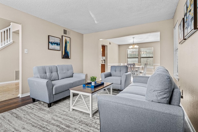 living room featuring wood-type flooring, a textured ceiling, and an inviting chandelier