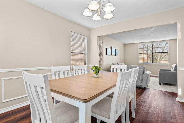 dining area featuring dark wood-type flooring and a notable chandelier