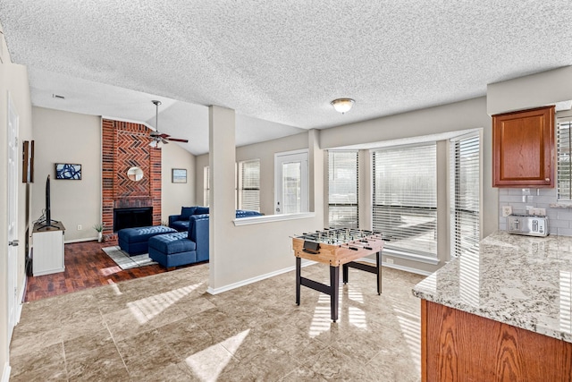 dining room with ceiling fan, a fireplace, and vaulted ceiling