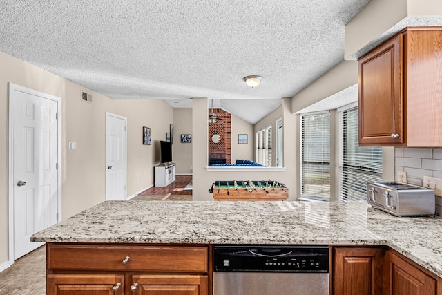 kitchen featuring backsplash, light stone countertops, stainless steel dishwasher, and a textured ceiling