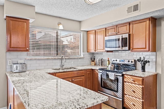 kitchen with light stone counters, sink, appliances with stainless steel finishes, and tasteful backsplash