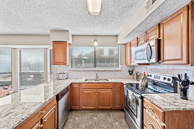 kitchen featuring light stone counters, sink, appliances with stainless steel finishes, and tasteful backsplash