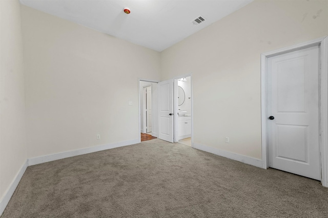 unfurnished bedroom featuring light colored carpet and ensuite bath