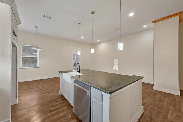 kitchen featuring pendant lighting, stainless steel dishwasher, sink, and a center island with sink