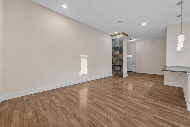 unfurnished living room with hardwood / wood-style flooring and a tile fireplace