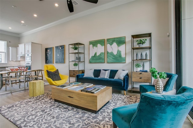 living room featuring ceiling fan, crown molding, and light hardwood / wood-style flooring