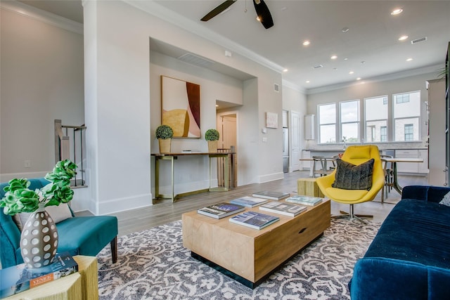 living room with ceiling fan, light wood-type flooring, and crown molding