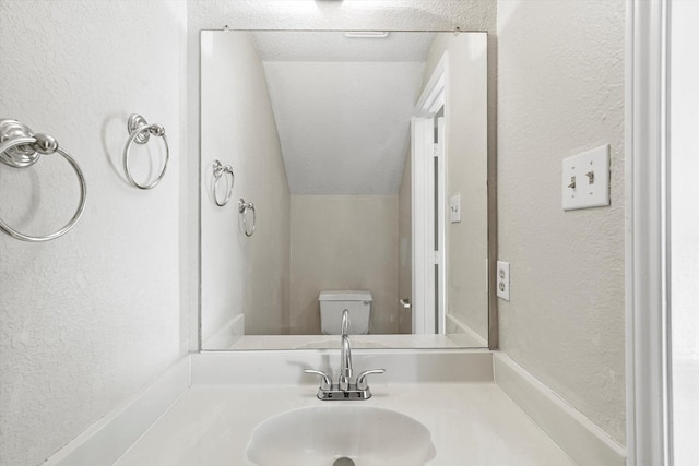 bathroom with sink, a textured ceiling, and toilet