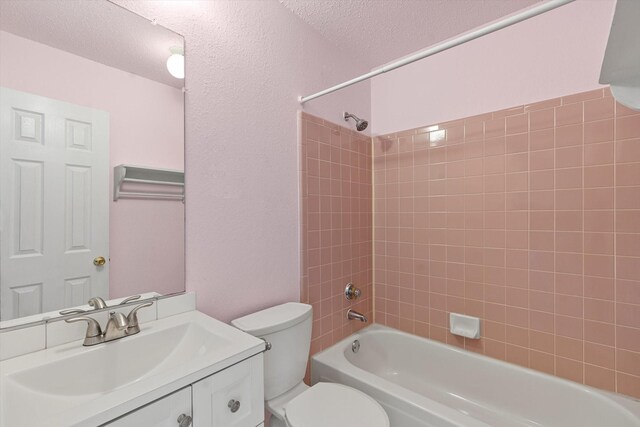 full bathroom with vanity, tiled shower / bath, a textured ceiling, and toilet