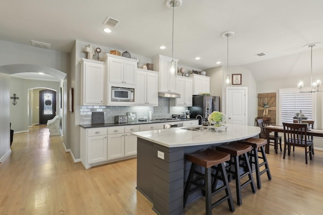 kitchen featuring decorative backsplash, appliances with stainless steel finishes, white cabinetry, and pendant lighting