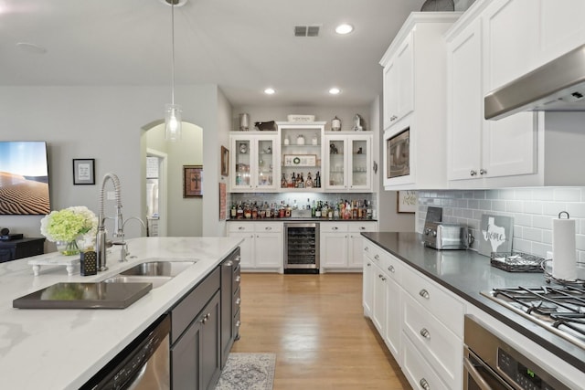 kitchen featuring white cabinetry, hanging light fixtures, wine cooler, dark stone counters, and appliances with stainless steel finishes