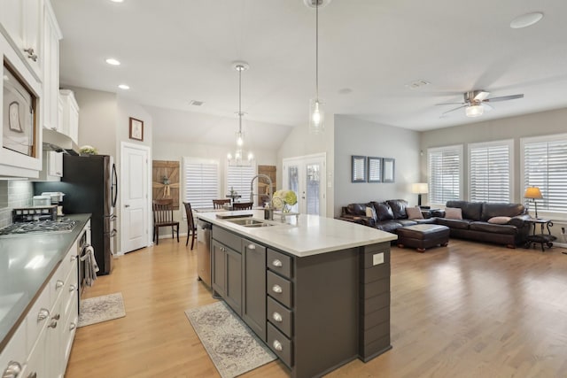 kitchen with sink, stainless steel appliances, hanging light fixtures, a center island with sink, and white cabinets