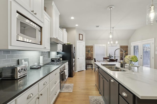 kitchen with white cabinets, pendant lighting, a center island with sink, and appliances with stainless steel finishes