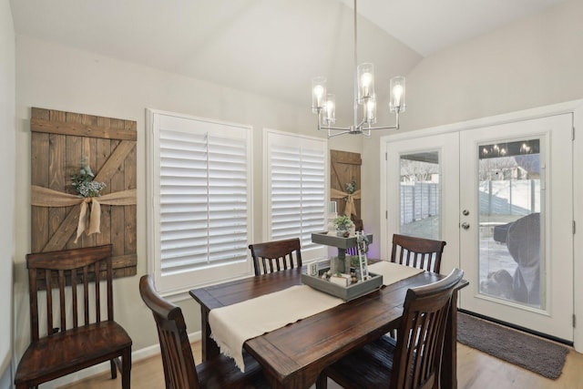 dining room with french doors, lofted ceiling, light hardwood / wood-style flooring, and a chandelier