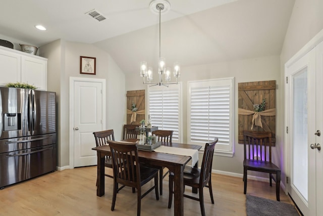 dining area featuring light wood-type flooring, lofted ceiling, and a notable chandelier