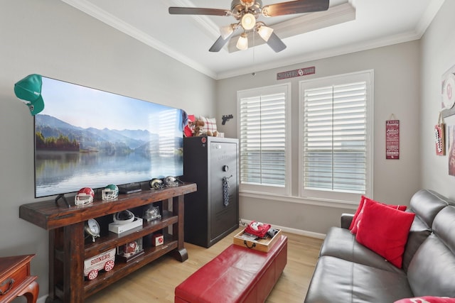 living room featuring light wood-type flooring, a raised ceiling, ceiling fan, and crown molding