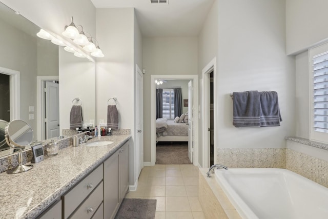 bathroom featuring tile patterned floors, vanity, and tiled bath