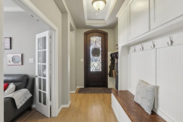 mudroom with a tray ceiling, light hardwood / wood-style flooring, and ornamental molding