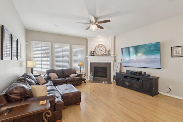 living room featuring ceiling fan, a fireplace, and wood-type flooring