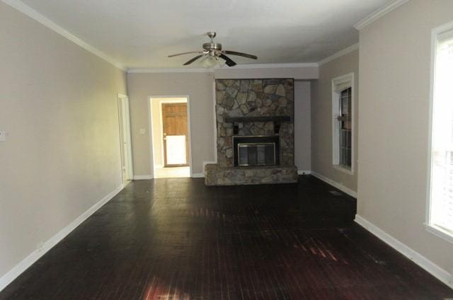 unfurnished living room featuring dark wood-type flooring, ceiling fan, ornamental molding, and a fireplace