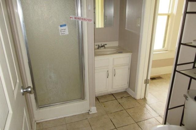 bathroom with tile patterned flooring, vanity, and walk in shower