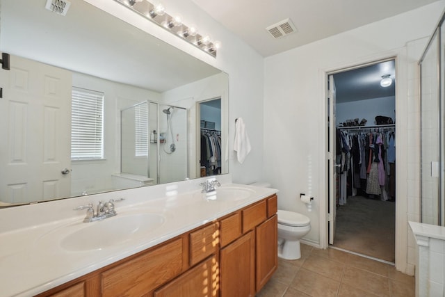 bathroom featuring tile patterned flooring, vanity, an enclosed shower, and toilet