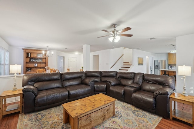 living room featuring ceiling fan with notable chandelier and light hardwood / wood-style flooring