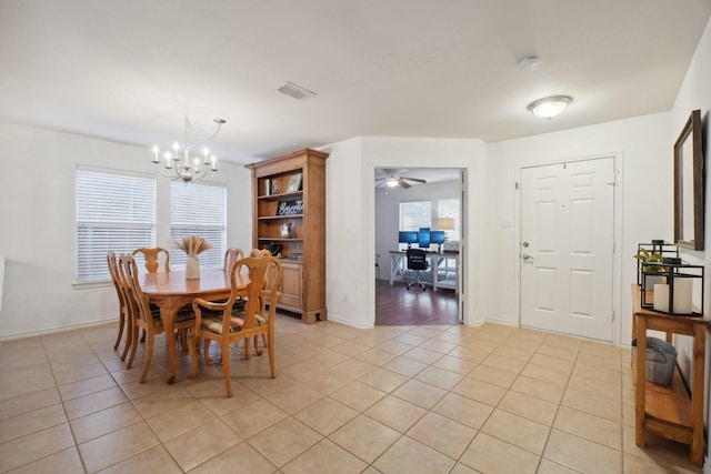 tiled dining space with ceiling fan with notable chandelier