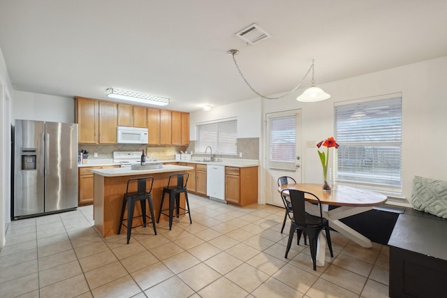 kitchen featuring sink, tasteful backsplash, decorative light fixtures, a center island, and white appliances