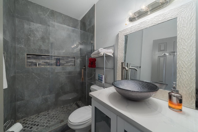 bathroom with tiled shower, vanity, and toilet