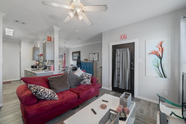 living room with crown molding, ceiling fan, sink, and hardwood / wood-style flooring