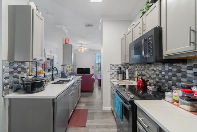 kitchen with tasteful backsplash, dishwasher, sink, gray cabinetry, and black electric range