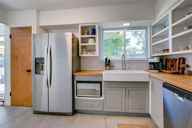 kitchen featuring gray cabinetry, sink, stainless steel appliances, and wooden counters