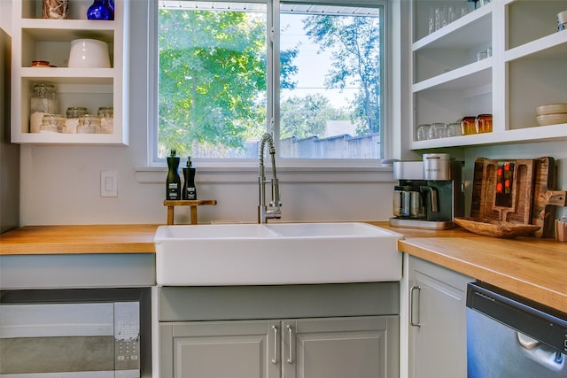 interior space with stainless steel dishwasher, wood counters, plenty of natural light, and sink