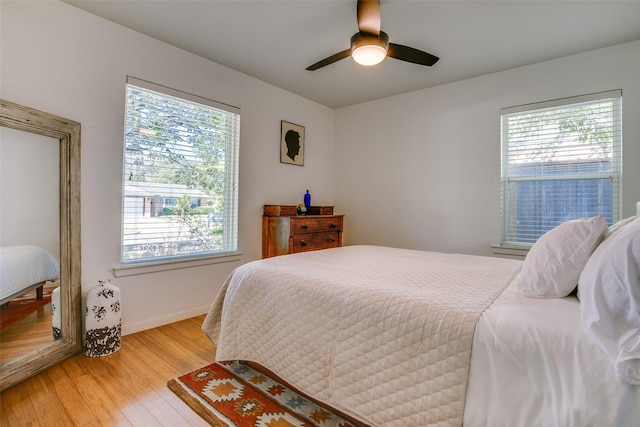 bedroom featuring ceiling fan, light hardwood / wood-style floors, and multiple windows