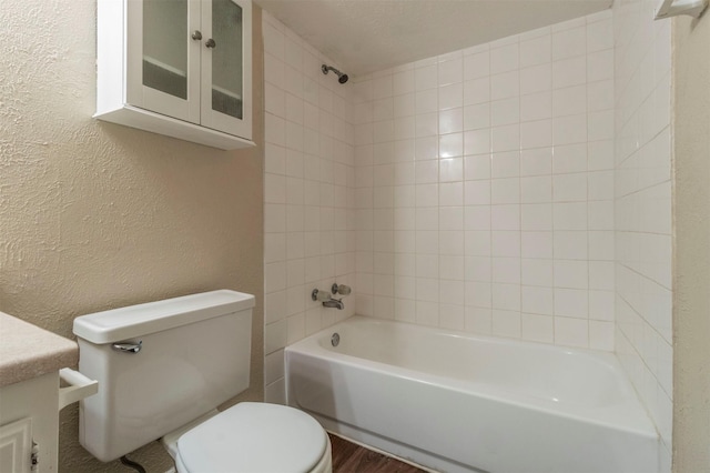 full bathroom featuring tiled shower / bath, vanity, and toilet