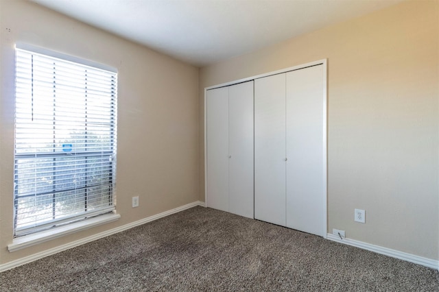 unfurnished bedroom featuring multiple windows, carpet floors, and a closet