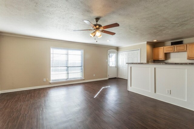 unfurnished living room featuring a textured ceiling, ceiling fan, crown molding, and dark wood-type flooring