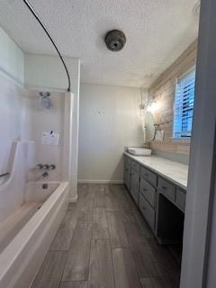 bathroom featuring hardwood / wood-style floors, a textured ceiling, vanity, and shower / tub combination