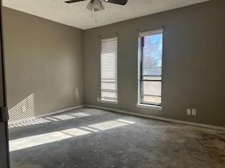 empty room with concrete flooring, a wealth of natural light, and ceiling fan