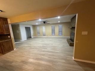 unfurnished living room featuring a fireplace, ceiling fan, and light wood-type flooring