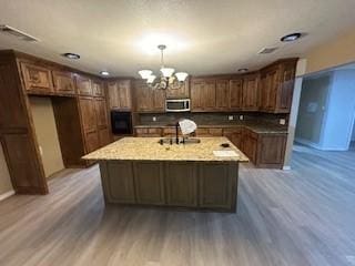 kitchen featuring a center island with sink, pendant lighting, sink, and dark wood-type flooring