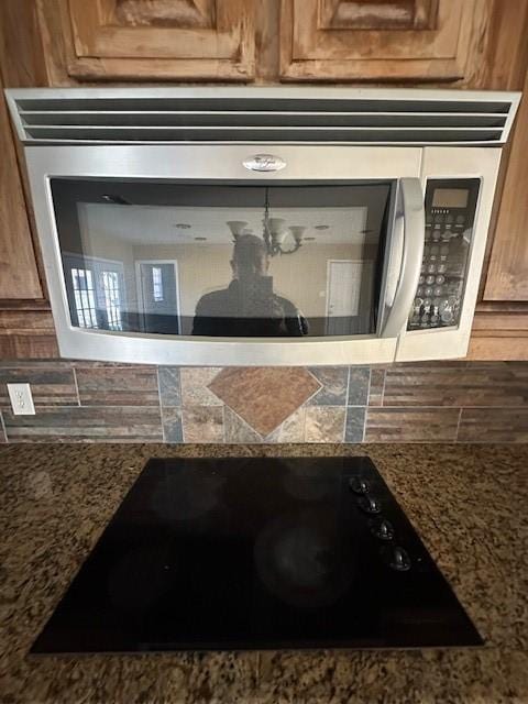 interior details featuring black electric stovetop, stone counters, and tasteful backsplash