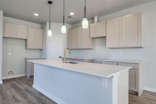 kitchen featuring a center island with sink, sink, hanging light fixtures, and light hardwood / wood-style flooring