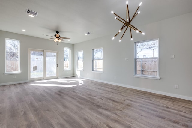 unfurnished living room featuring ceiling fan with notable chandelier and light wood-type flooring