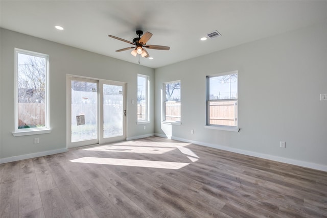 spare room featuring a healthy amount of sunlight, ceiling fan, and light hardwood / wood-style floors