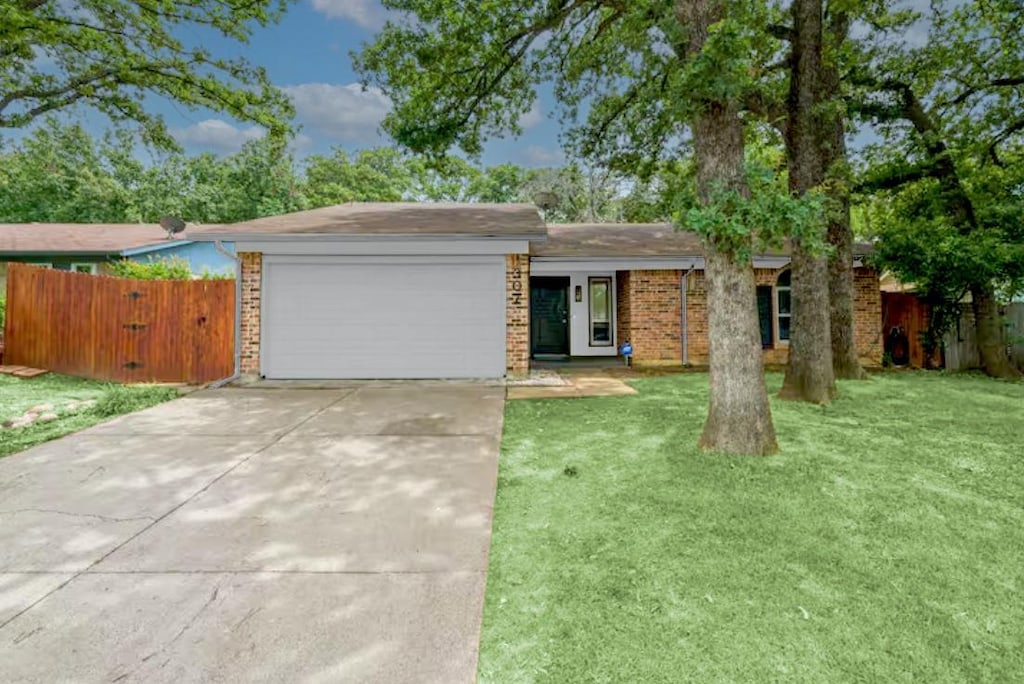 ranch-style house featuring a front lawn, brick siding, driveway, and an attached garage